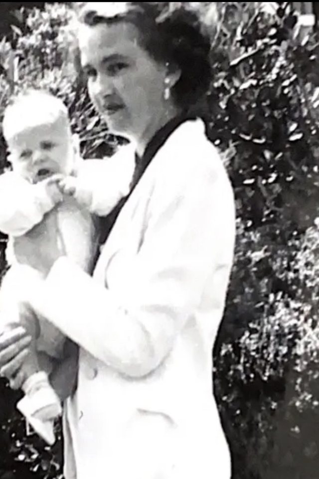 A black and white photograph from decades ago: a woman holding a baby.