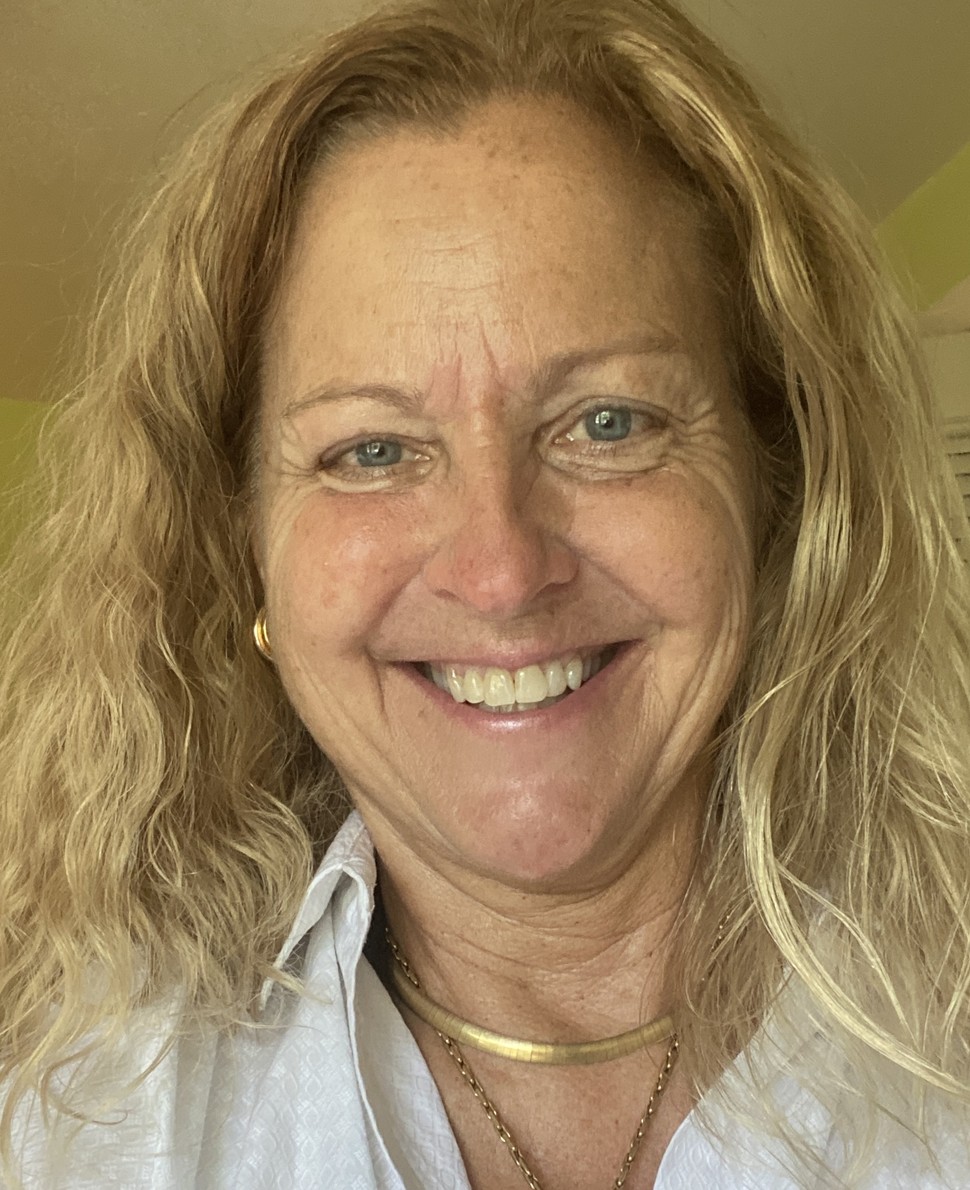 A woman smiling at the camera, photographed indoors.