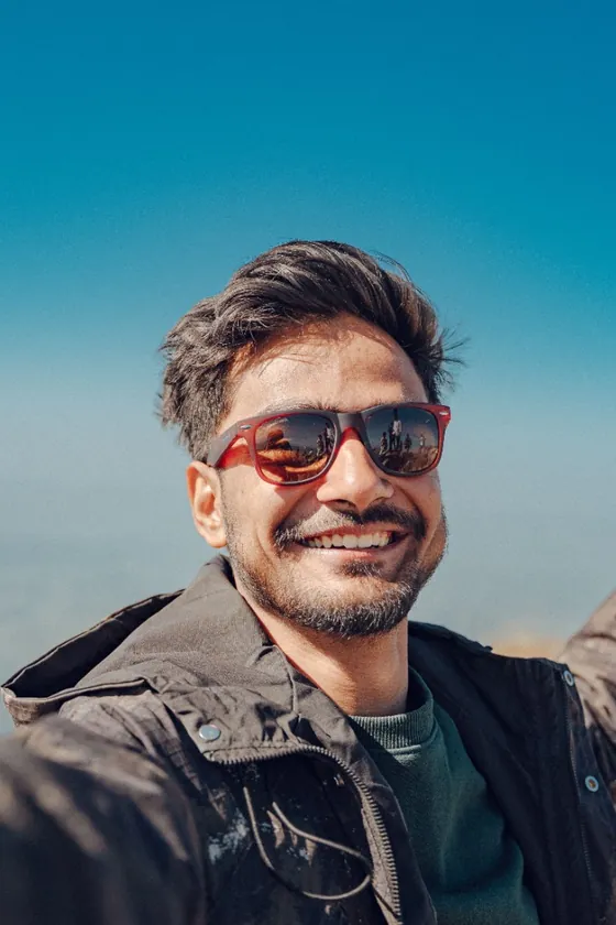 A man smiling on a hillside under a blue sky